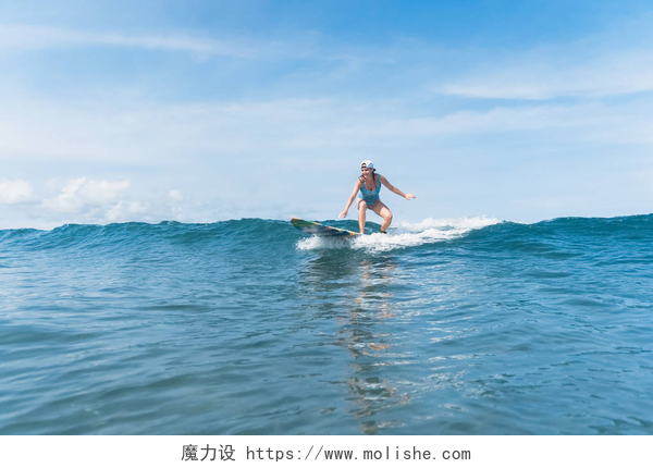 一个女人在海洋里冲浪游泳衣和帽子的妇女在海洋冲浪